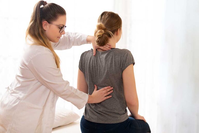 Parent and child speaking with a healthcare provider about a child’s back pain in a bright examination room.